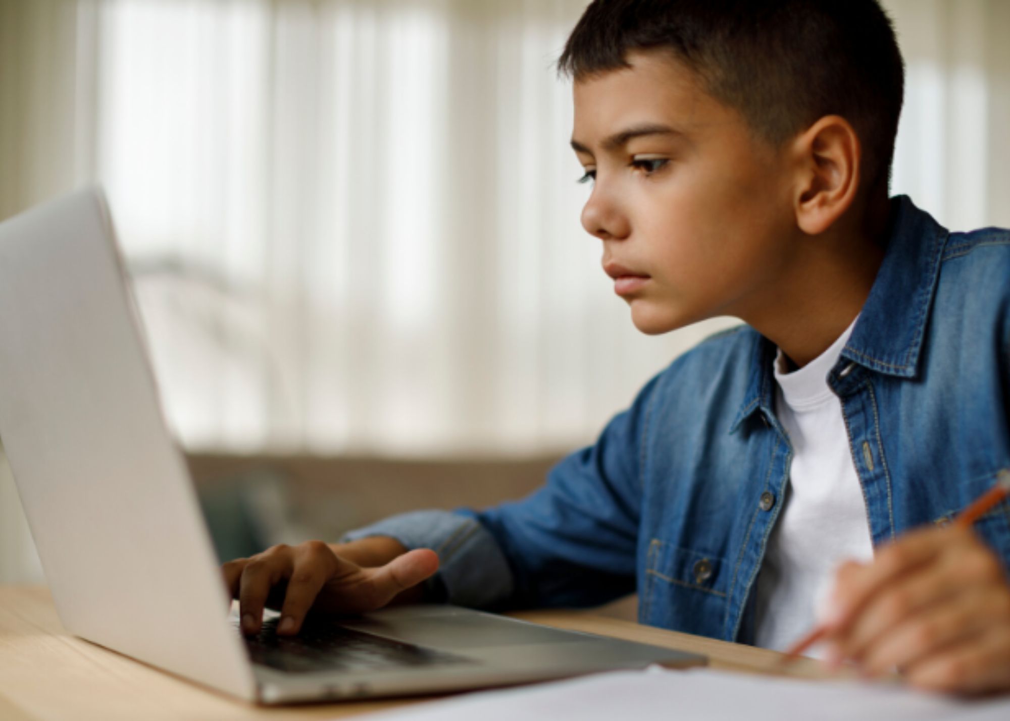 Young boy doing his online school work on a laptop